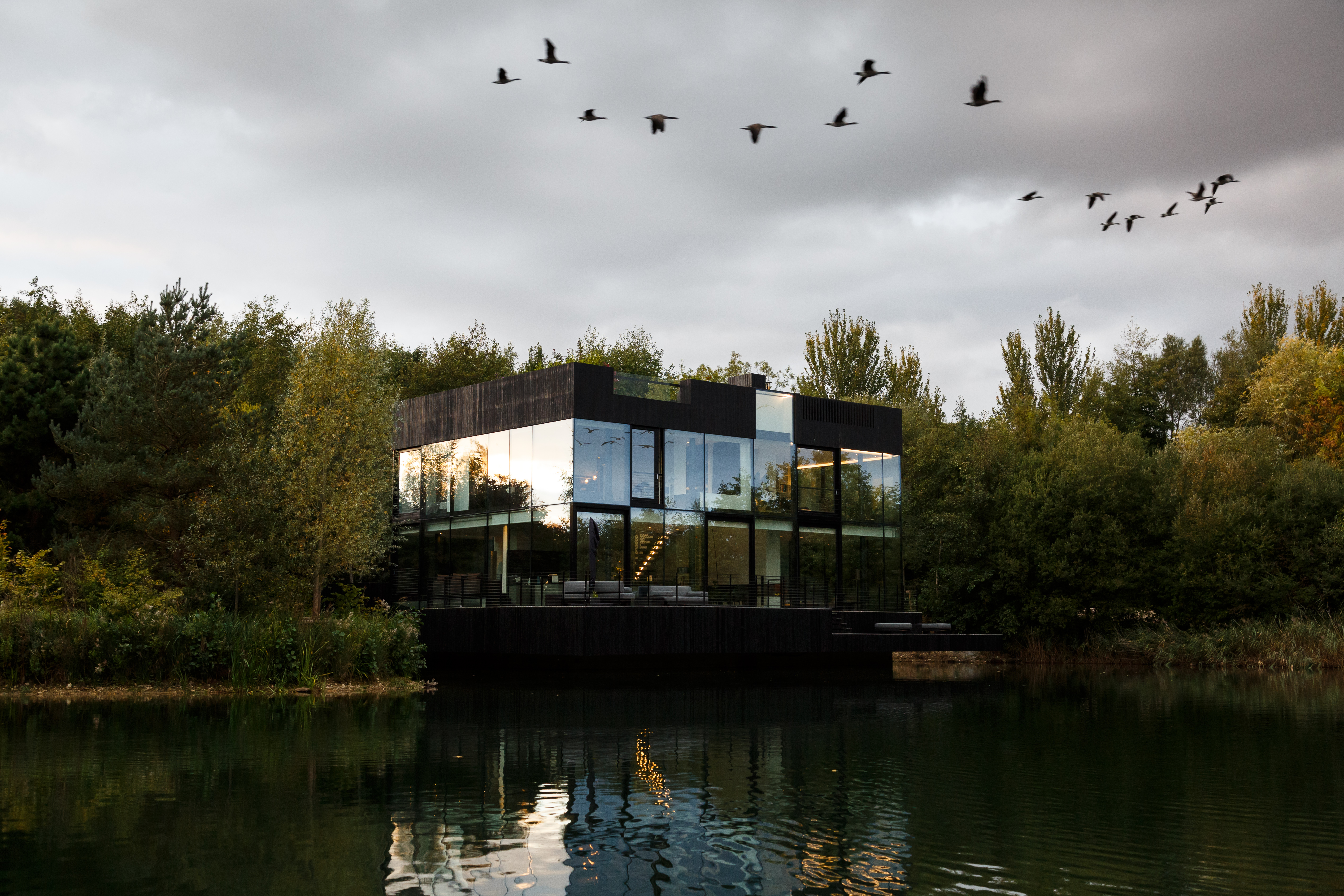 The Glass House exterior - Shou Sugi Ban timber and triple-glazed glass set within natural lakeside habitat